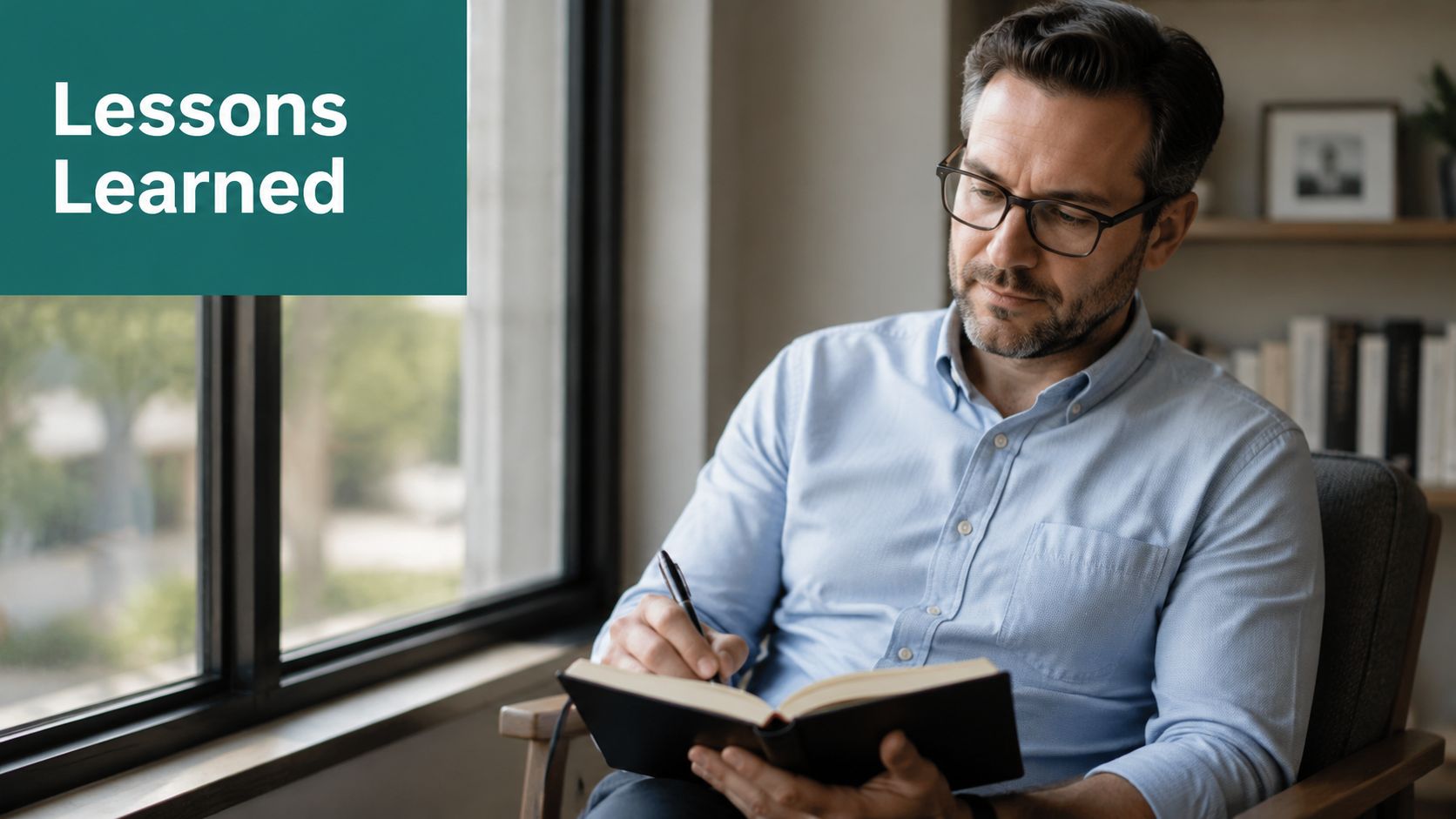 A professional man with glasses sitting in a chair and thoughtfully writing in his notebook.